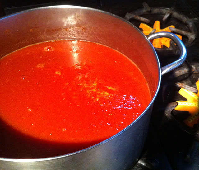 Tomatoes cooking down for paste, on summer kitchen stove.