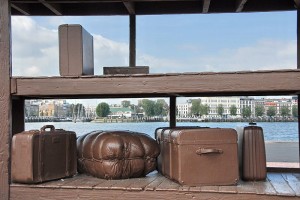 This Rotterdamn scup[ture,  ‘Lost Luggage Depot’ was made by the Canadian plastic artist Jeff Wall (1946-). It is made of cast iron and symbolizes the goodbye of the many emigrants to their former lives. Image: Rotterdam 'Kop van Zuid', Creative Commons