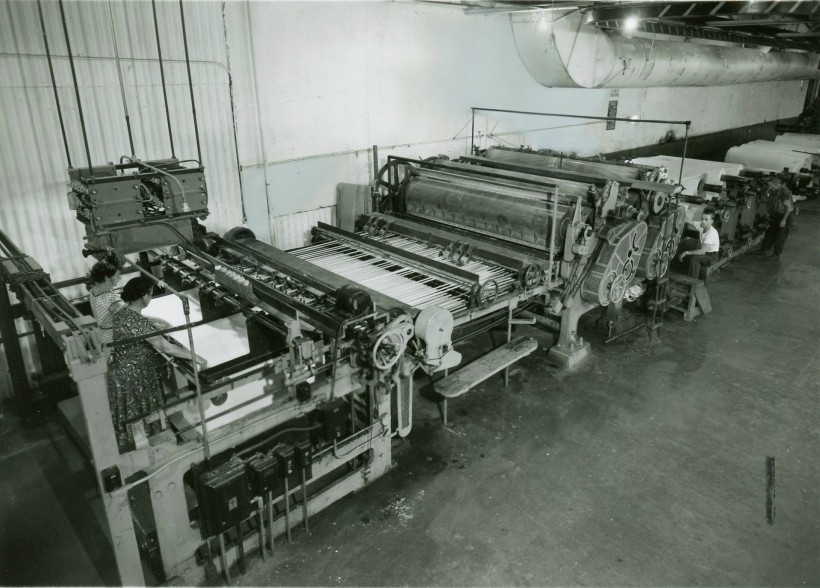 Two women and a man cutting paper at the "Cutting Machine". 