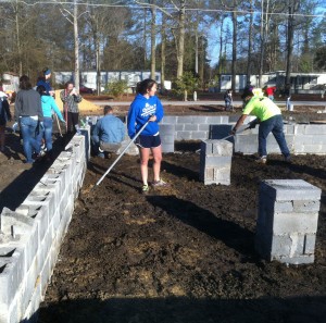 Anna Hughes helping to level crawl space dirt inside foundation. Photo: Ellen Rocco